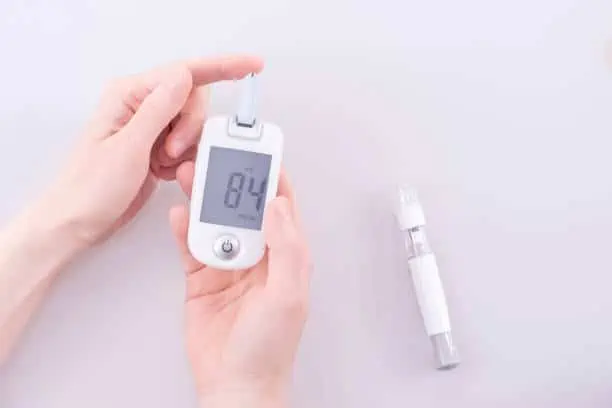 Human using a glucometer to measure and test blood glucose levels from a finger