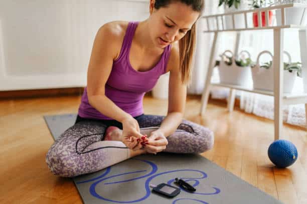 Sporty woman is measuring blood sugar or ketones level after exercising.