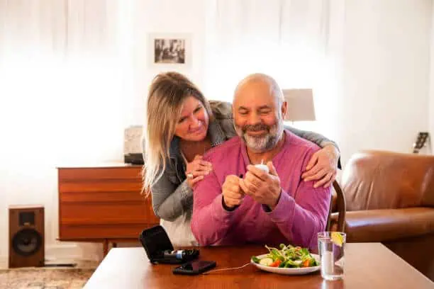 A diabetic patient checking his blood sugar at home with the support of his wife. Consistent monitoring of blood sugar is an important part of managing diabetes. Photographed in North America